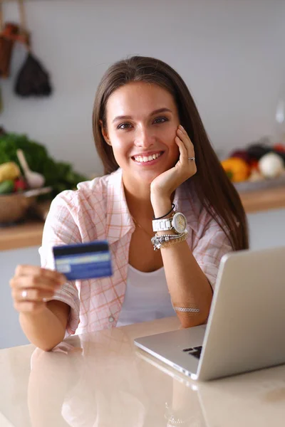 Lachende vrouw online winkelen met behulp van Tablet PC- en creditcard in keuken — Stockfoto