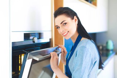 Güzel genç bayan pastasının fırında ne yaptığını kontrol ediyor.