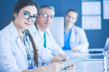 Ciddi bir tıbbi ekip parlak bir ofiste dizüstü bilgisayar kullanıyor.