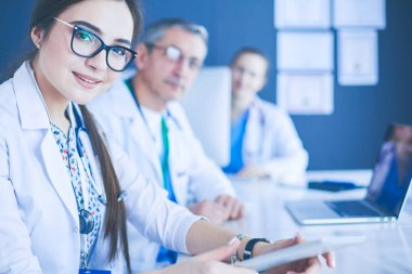 Ciddi bir tıbbi ekip parlak bir ofiste dizüstü bilgisayar kullanıyor.