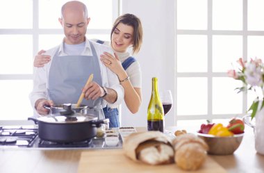 Couple cooking together in the kitchen at home clipart