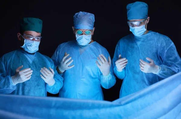 Grupo de cirujanos trabajando en quirófano tonificado en azul. Equipo médico realizando la operación —  Fotos de Stock