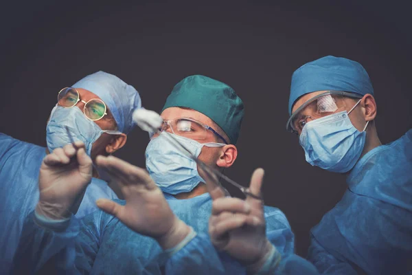Grupa chirurgów w pracy w sali operacyjnej stonowana na niebiesko. Zespół medyczny wykonujący operację — Zdjęcie stockowe