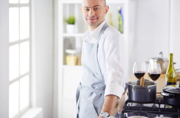 Handsome man is cooking on kitchen and smiling
