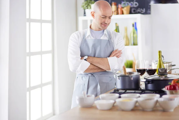 Handsome man is cooking on kitchen and smiling