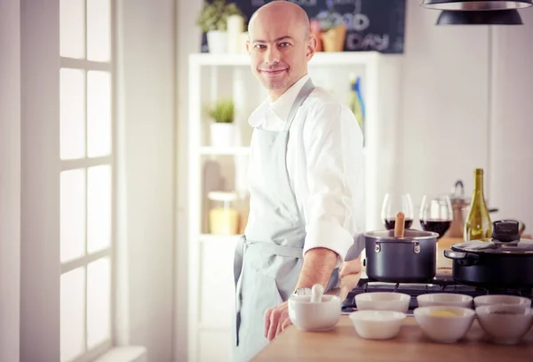 Handsome man is cooking on kitchen and smiling