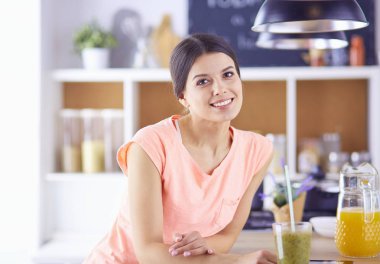 Mutfakta dijital tablet kullanan güzel genç bir kadın.