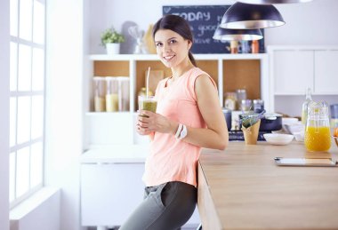 Mutfakta dijital tablet kullanan güzel genç bir kadın.