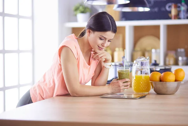 Όμορφη νεαρή γυναίκα χρησιμοποιώντας ένα ψηφιακό tablet στην κουζίνα — Φωτογραφία Αρχείου