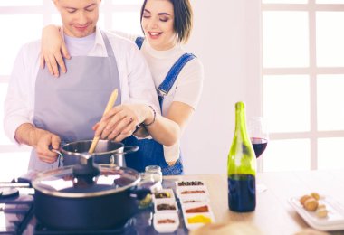 Evdeki mutfakta birlikte yemek pişiren çift.
