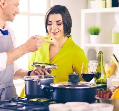 Couple cooking together in the kitchen at home clipart