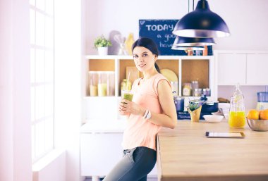Mutfakta dijital tablet kullanan güzel genç bir kadın.