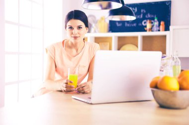 Mutfakta dizüstü bilgisayara benzeyen tariflerle gülümseyen genç bir kadın. Gıda blogcusu kavramı