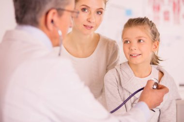 Steteskoplu kız ve doktor kalp atışlarını dinliyor.