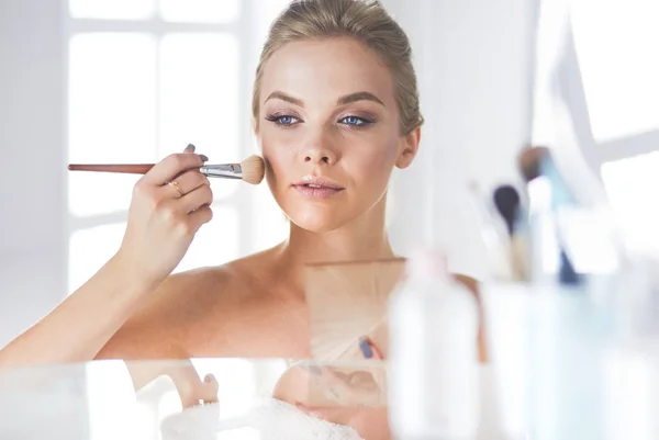 Uma foto de uma jovem mulher aplicando pó facial no banheiro — Fotografia de Stock