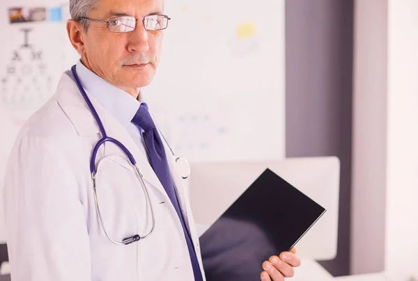 Man dokter schrijft notities op het klembord in het ziekenhuis — Stockfoto