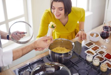 Evdeki mutfakta birlikte yemek pişiren çift.