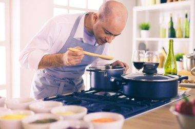 Yakışıklı adam mutfakta yemek yapıyor ve gülümsüyor.