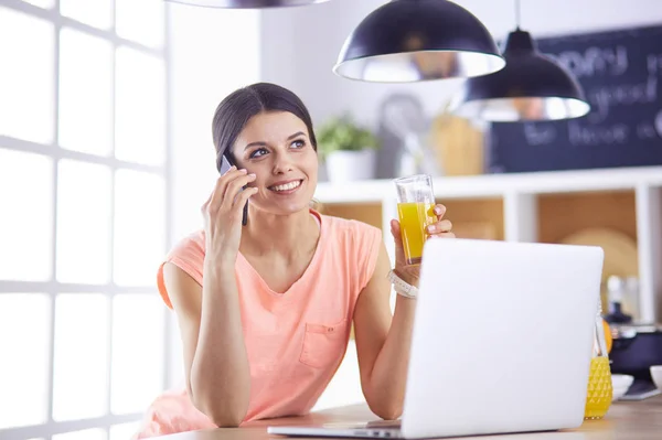 Ung kvinna i köket med bärbar dator ser recept, leende. Begreppet livsmedelsbloggare — Stockfoto