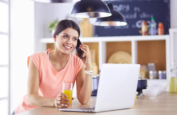 Ung kvinna i köket med bärbar dator ser recept, leende. Begreppet livsmedelsbloggare — Stockfoto