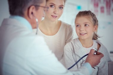 Steteskoplu kız ve doktor kalp atışlarını dinliyor.