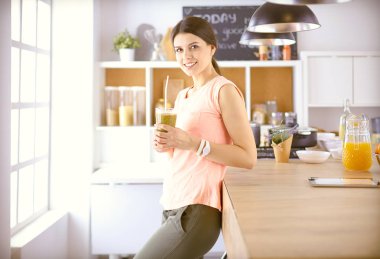 Mutfakta dijital tablet kullanan güzel genç bir kadın.