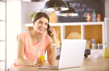 Mutfakta dizüstü bilgisayara benzeyen tariflerle gülümseyen genç bir kadın. Gıda blogcusu kavramı