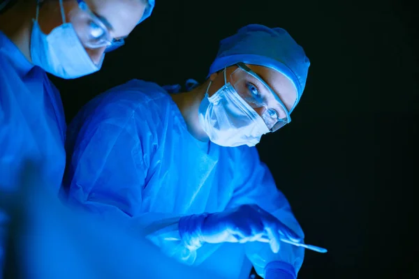 Artsen team in de chirurgie in een donkere achtergrond. — Stockfoto
