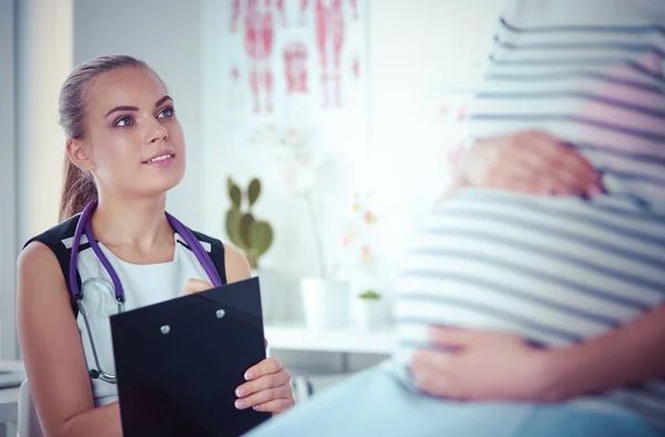 Jonge vrouwelijke arts met stethoscoop en tablet in het ziekenhuis in gesprek met zwangere vrouw. — Stockfoto