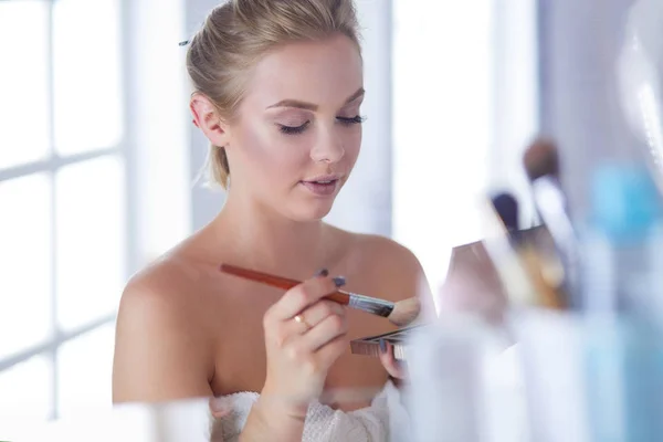 A picture of a young woman applying face powder in the bathroom — Stock Photo, Image