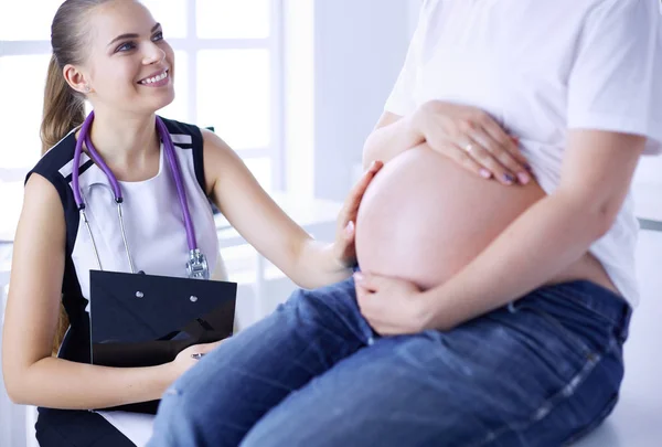 Doctora joven examinando a una mujer embarazada en la clínica. —  Fotos de Stock