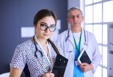 Bir doktor ekibi, kadın ve erkek, ofiste bekliyorlar.