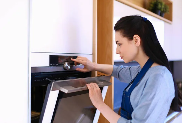 Mulher bonita verificando como seu bolo está indo no forno — Fotografia de Stock