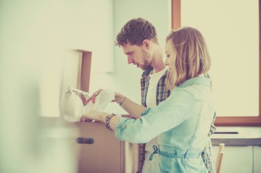 Genç bir çift yeni evinde büyük bir karton kutu taşıyor. Taşınıyorlar.