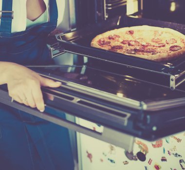 Mutlu genç bayan evde pizza pişiriyor.