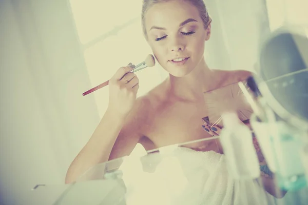 A picture of a young woman applying face powder in the bathroom — Stock Photo, Image