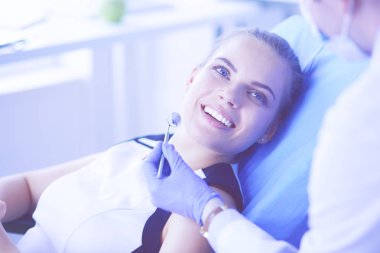 Güzel gülüşü olan genç bir bayan hasta dişçi muayenesi için dişçiye gidiyor..