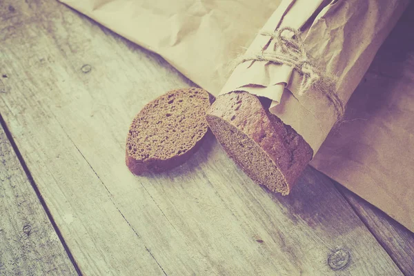 Brood in plakjes, verpakt in papier op houten tafel. — Stockfoto