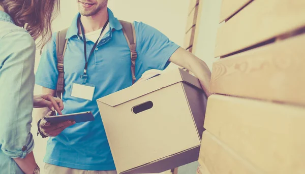 Repartidor sonriente en uniforme azul que entrega la caja de paquetes al destinatario - concepto de servicio de mensajería — Foto de Stock