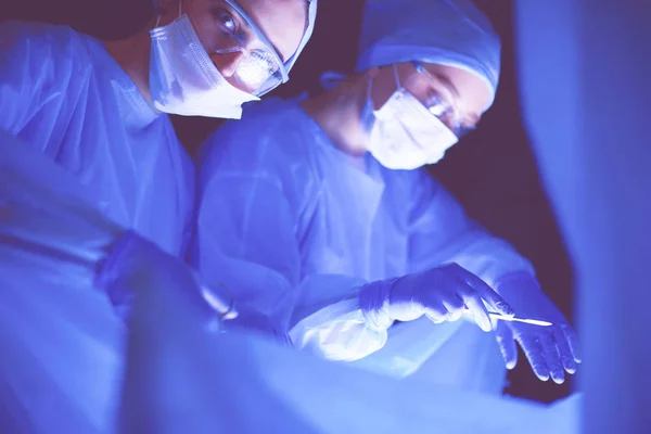 Lékaři tým v chirurgii v tmavém pozadí. — Stock fotografie