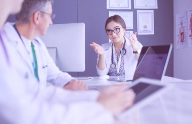 Ciddi bir tıbbi ekip parlak bir ofiste dizüstü bilgisayar kullanıyor.