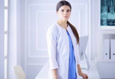 Hastanedeki beyaz önlüklü genç kadın portresi.