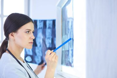 Stetoskop lu genç gülümseyen kadın doktor doktor ofisinde röntgeni işaret ediyor