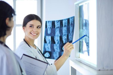İki gülümseyen doktor hastane muayene odasında röntgenleri gösteriyor.