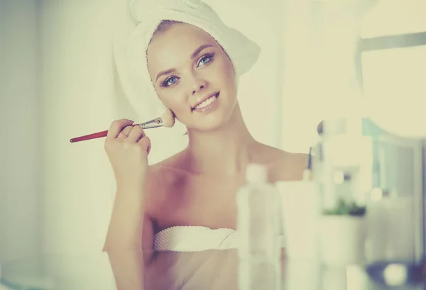 Uma foto de uma jovem mulher aplicando pó facial no banheiro — Fotografia de Stock