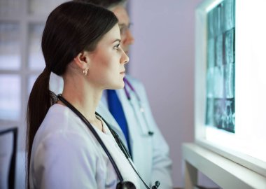 Bir grup doktor bir klinikte röntgenleri inceliyor, teşhis koymayı düşünüyorlar.