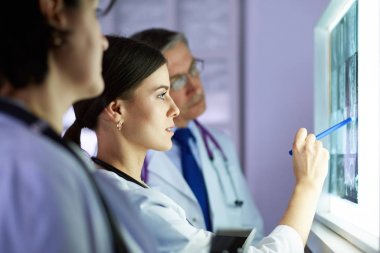 Bir grup doktor bir klinikte röntgenleri inceliyor, teşhis koymayı düşünüyorlar.