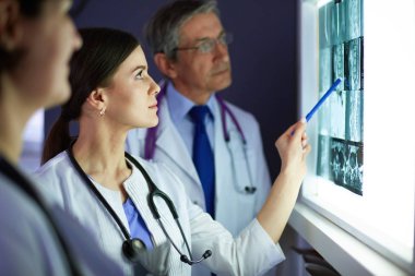 Bir grup doktor bir klinikte röntgenleri inceliyor, teşhis koymayı düşünüyorlar.