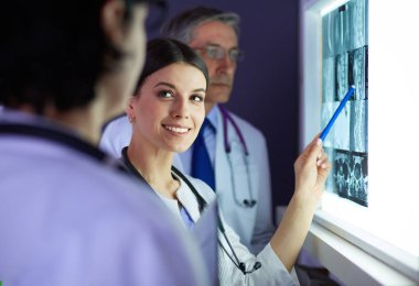 Bir grup doktor bir klinikte röntgenleri inceliyor, teşhis koymayı düşünüyorlar.