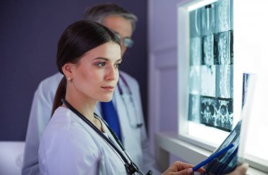 Bir grup doktor bir klinikte röntgenleri inceliyor, teşhis koymayı düşünüyorlar.